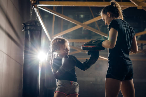 istock Small girl having a boxing training with her coach in a gym. 698620176