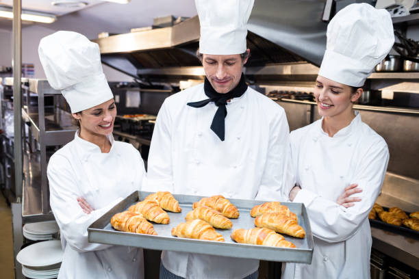 istock Three chefs holding a tray of baked croissant 698629524