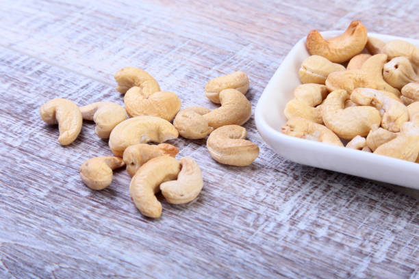 istock nuts cashews in white bowl on wooden background. Selective focus. 698634584