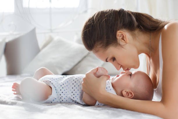 istock Mother playing with her newborn son lying on bed 698635970