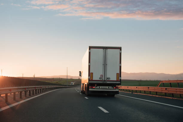 istock White truck driving on two lane highway during sunset 698645748