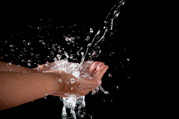 istock hand and pouring water on black background 698655954