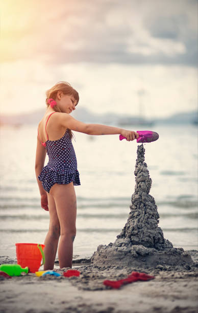 Little girl playing with water and sand at the beach