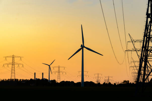 istock Overhead power line and wind turbines with a power plant 698677700