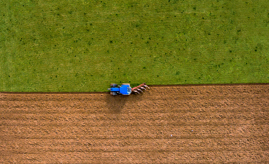Aerial photo of blue tractor plowing ploughing field
