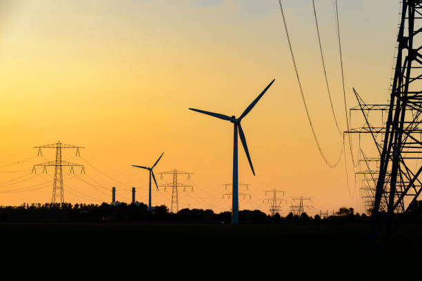 istock Overhead power line and wind turbines with a power plant 698678254