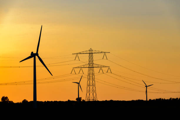 istock Overhead power line and wind turbines with a power plant 698682480