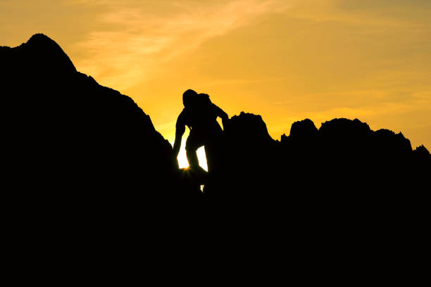 istock Silhouette of man climbing on rock mountain at sunset 698687998