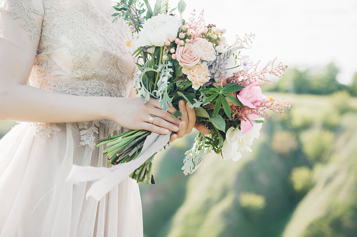 bride's hands hold a beautiful bridal bouquet of peony. fine art photography.