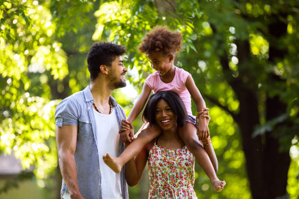 istock Mother carrying daughter on shoulders during walk in park 698718026