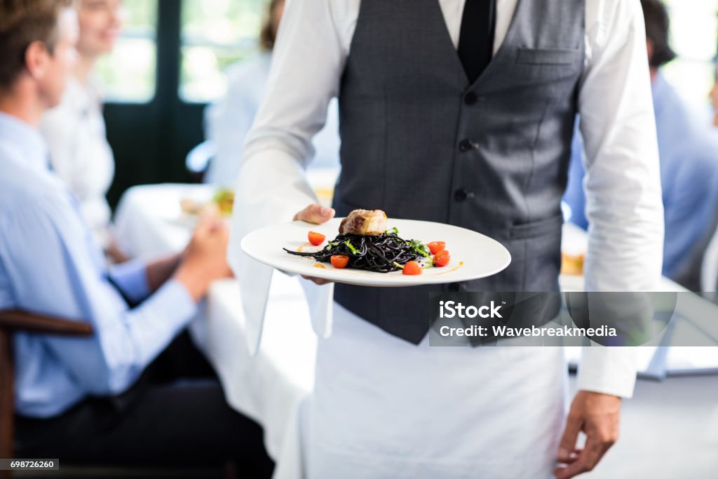 Waiter holding a plate of meal Close-up of waiter holding plate of meal in restaurant Waiter Stock Photo