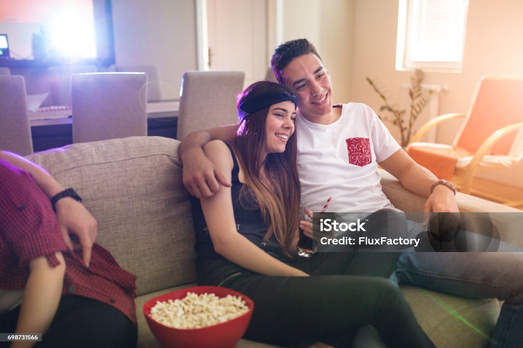 In his arms is nicer A young girl enjoys hugging her boyfriend while watching a movie. Tehy are real couple so emotions are real and candid. Teenager Stock Photo