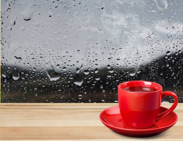 Rain. Red cup of coffee on wooden windowsill near glass window with raindrops rainy cafe stock pictures, royalty-free photos & images
