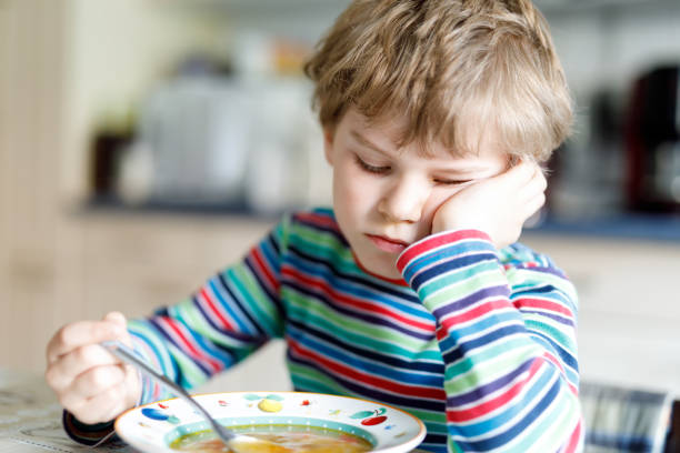 istock Adorable little school boy eating vegetable soup indoor. 698738520