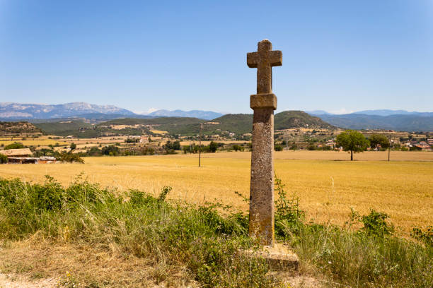 Stone croos in the Castellvell path in Solsona. Countryside summer landscape with Montsec range at background. Lleida, Catalonia, Spain.