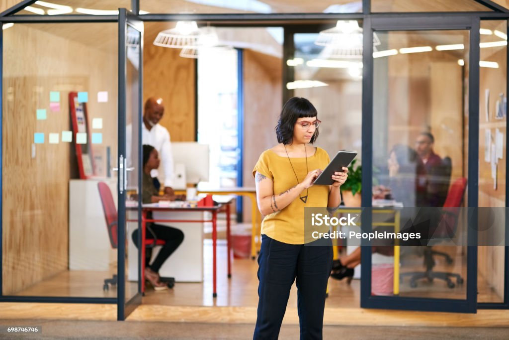 Another tech startup making its way up Shot of a young businesswoman using a digital tablet in the office Office Stock Photo