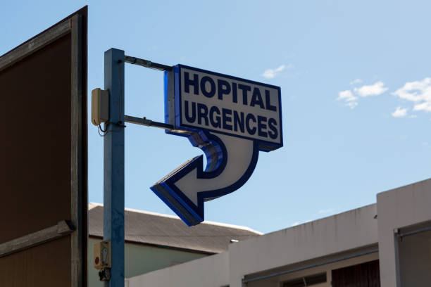 Road intersection stop sign and children's hospital entrance and cancer center directions sign at night.