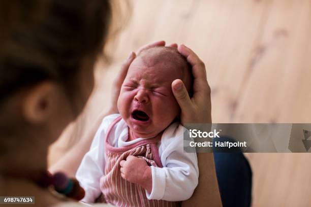 Unrecognizable Mother Holding Crying Newborn Baby Girl Stock Photo - Download Image Now