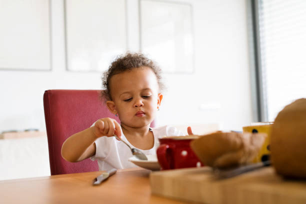 istock Little mixed-race girl at home having breakfast. 698764606
