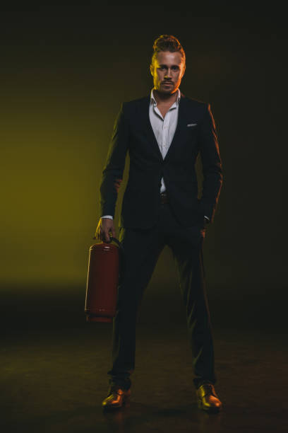 istock young stylish man in tuxedo standing and holding fire extinguisher 698772390