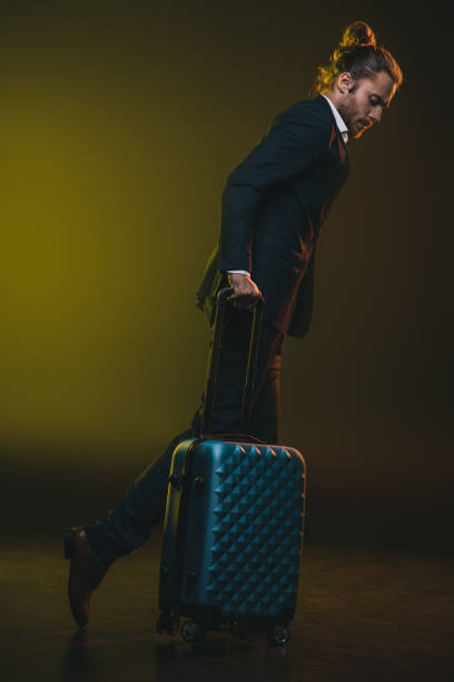 istock young stylish caucasian man in suit walking with suitcase 698772500