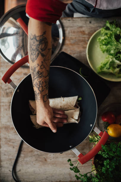 istock Tattooed cook is checking the warmth of wrap sandwiches 698778650