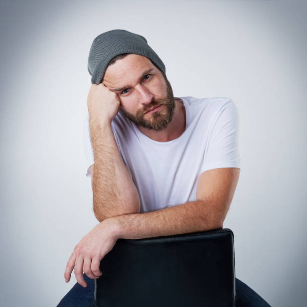 Portrait of a moody young man posing on a chair in the studio