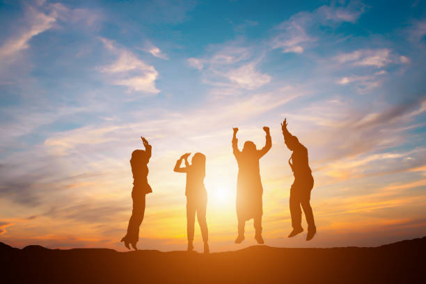 silueta de equipo de negocio feliz haciendo alta manos en fondo de cielo del atardecer por concepto de trabajo en equipo de negocios - sunset bay oregón fotografías e imágenes de stock