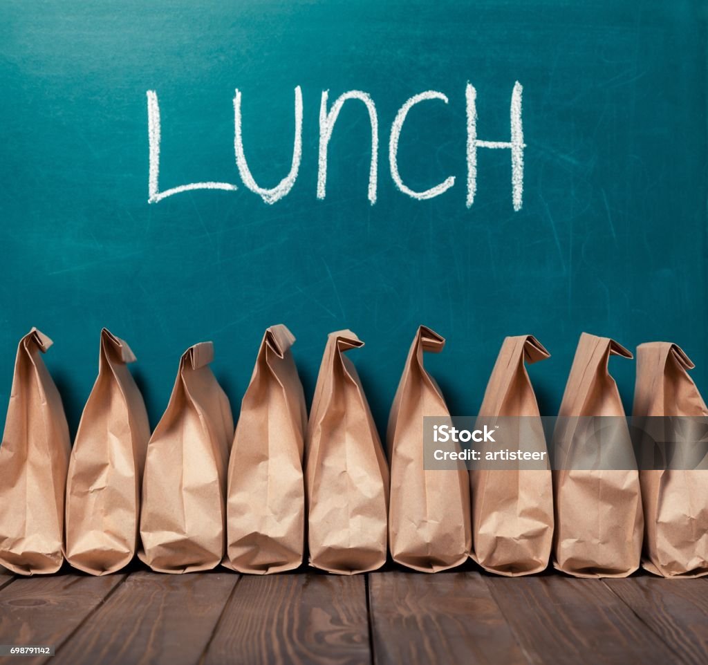 Lunch. Paper bags in row against blackboard background and word Lunch Lunch Stock Photo