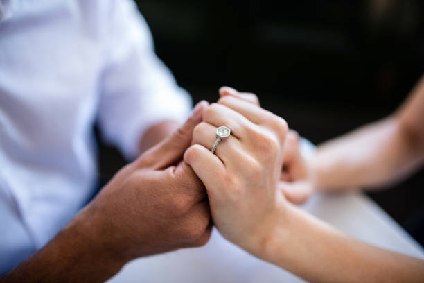 istock Close-up of couple holding hands with engagement ring 698808146