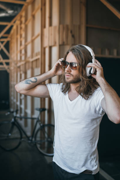 istock Handsome young long haired man adjusting headphones and looking away 698827856