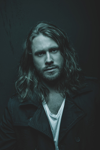 Portrait of handsome stylish bearded young man with long hair looking at camera