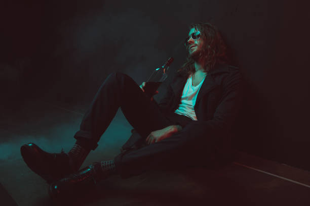 istock young drunkard in sunglasses drinking whiskey from bottle while sitting on the floor 698841292