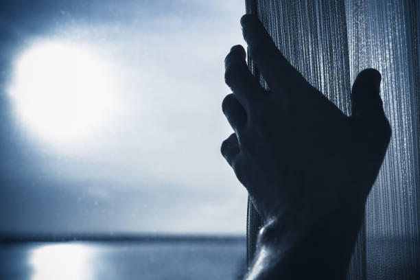 istock Male hand opens tulle on a window, blue toned 698841728