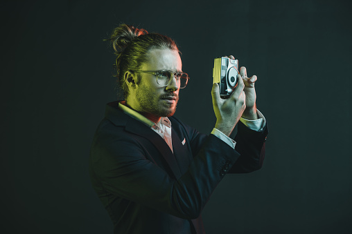 young caucasian man in tuxedo taking photo on point-and-shoot camera