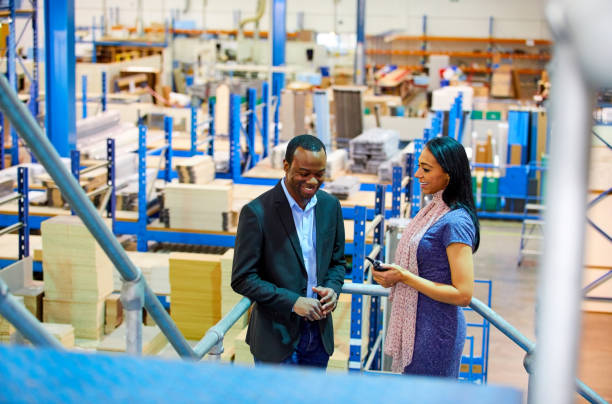 istock Two businesspeople discussing on a staircase in factory 698864272