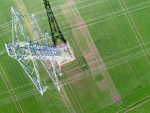 View of electricity pylon and power lines in field captured by drone