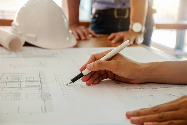 istock Architects engineer discussing at the table with blueprint - Closeup on hands and project print. 698883718