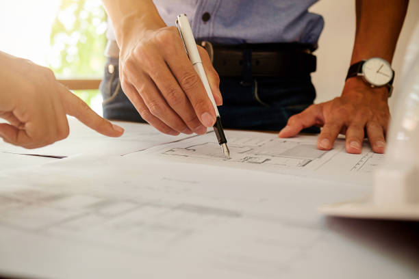 istock Architects engineer discussing at the table with blueprint - Closeup on hands and project print. 698883746