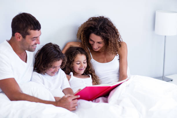 istock Family reading book together on bed 698891556