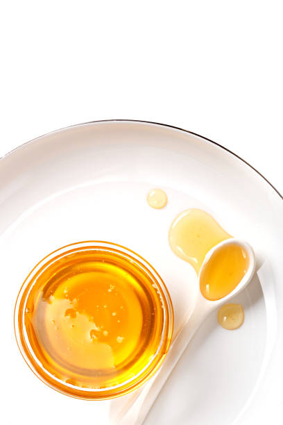 Honey in a little bowl with a spoon. White background. Top view