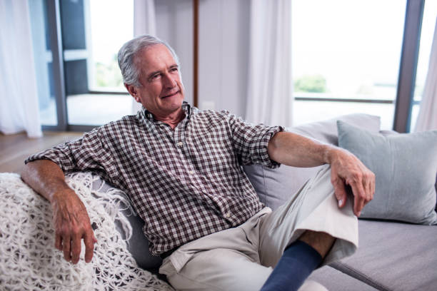 istock Senior man sitting on sofa in living room 698925196