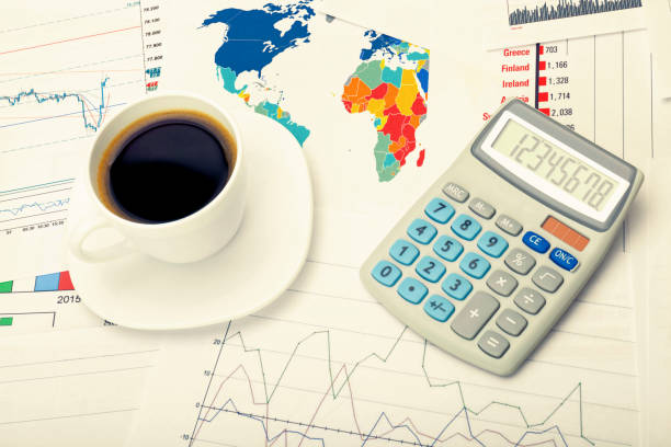 istock Coffee cup and calculator over world map and some financial documents - business concept 698944192