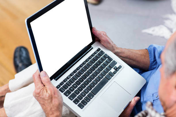 istock Senior man using laptop in living room 698949722