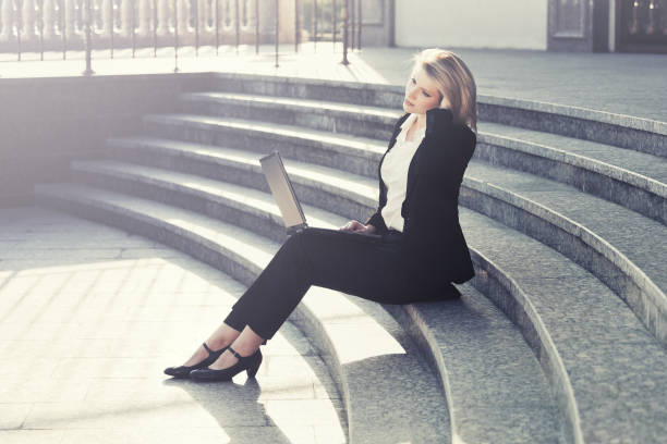 istock Young business woman using laptop on the steps 698965402