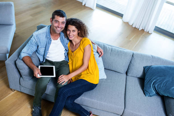 istock Portrait young couple sitting on sofa and using digital tablet 699021700