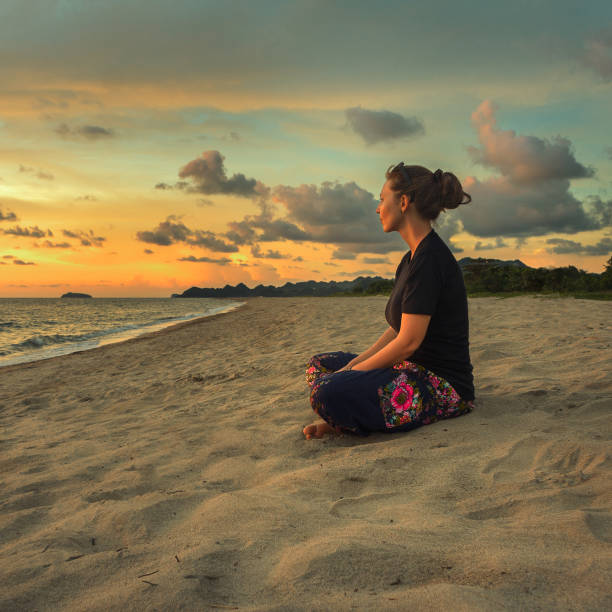 istock Woman meditating on the beach 699034602
