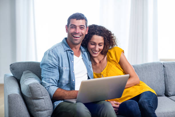 istock Young couple sitting on sofa and using laptop 699048086