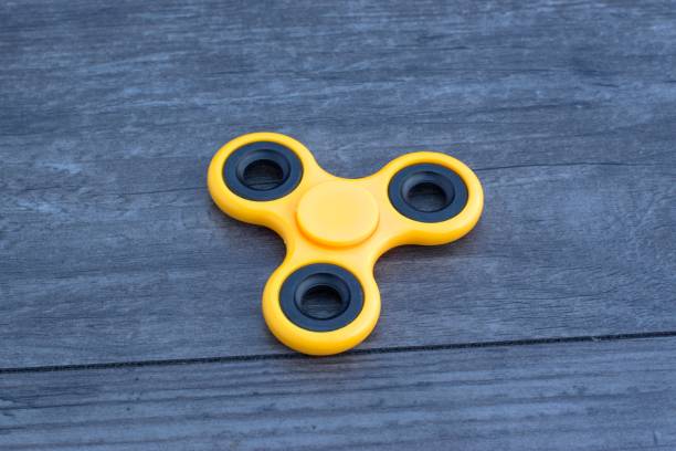 istock Yellow fidget spinner stress relieving toy on wooden background. 699067358