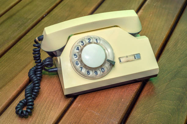 istock Old beige disk phone on wooden background 699083720